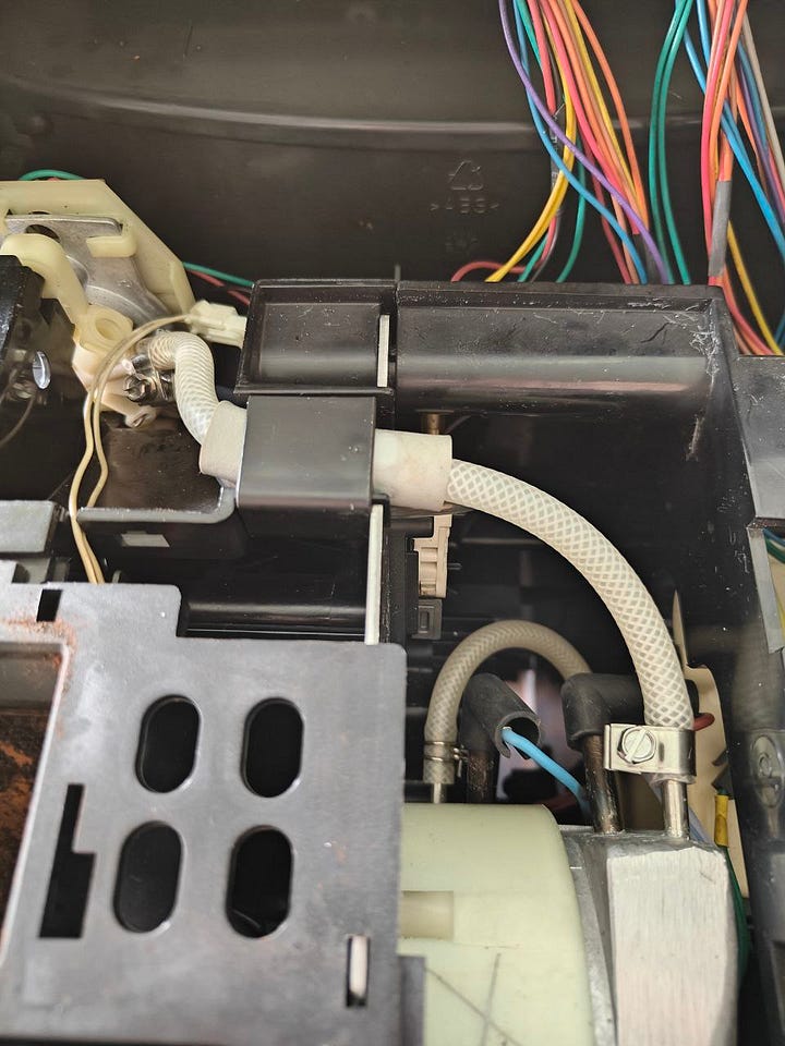 Internals of a coffee machine with a white tube, that I had to replace as the original one went boom